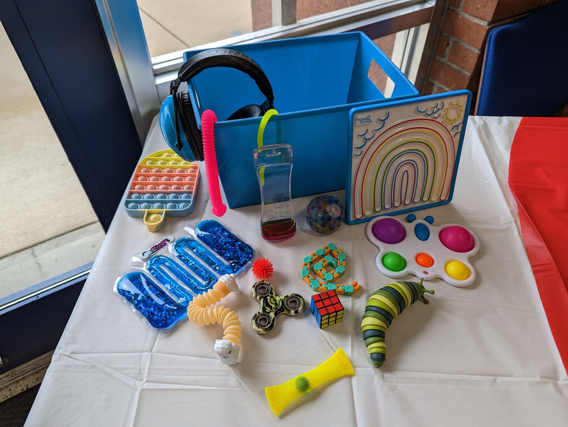 Sensory toy basket on a table with colorful fidgets, pop-its, spinners, and play items