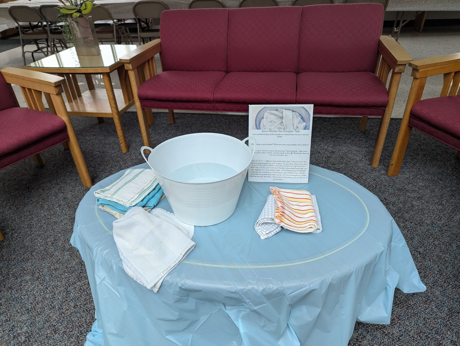 Aid table with basin and supplies in a lounge, beside red sofas and chairs.