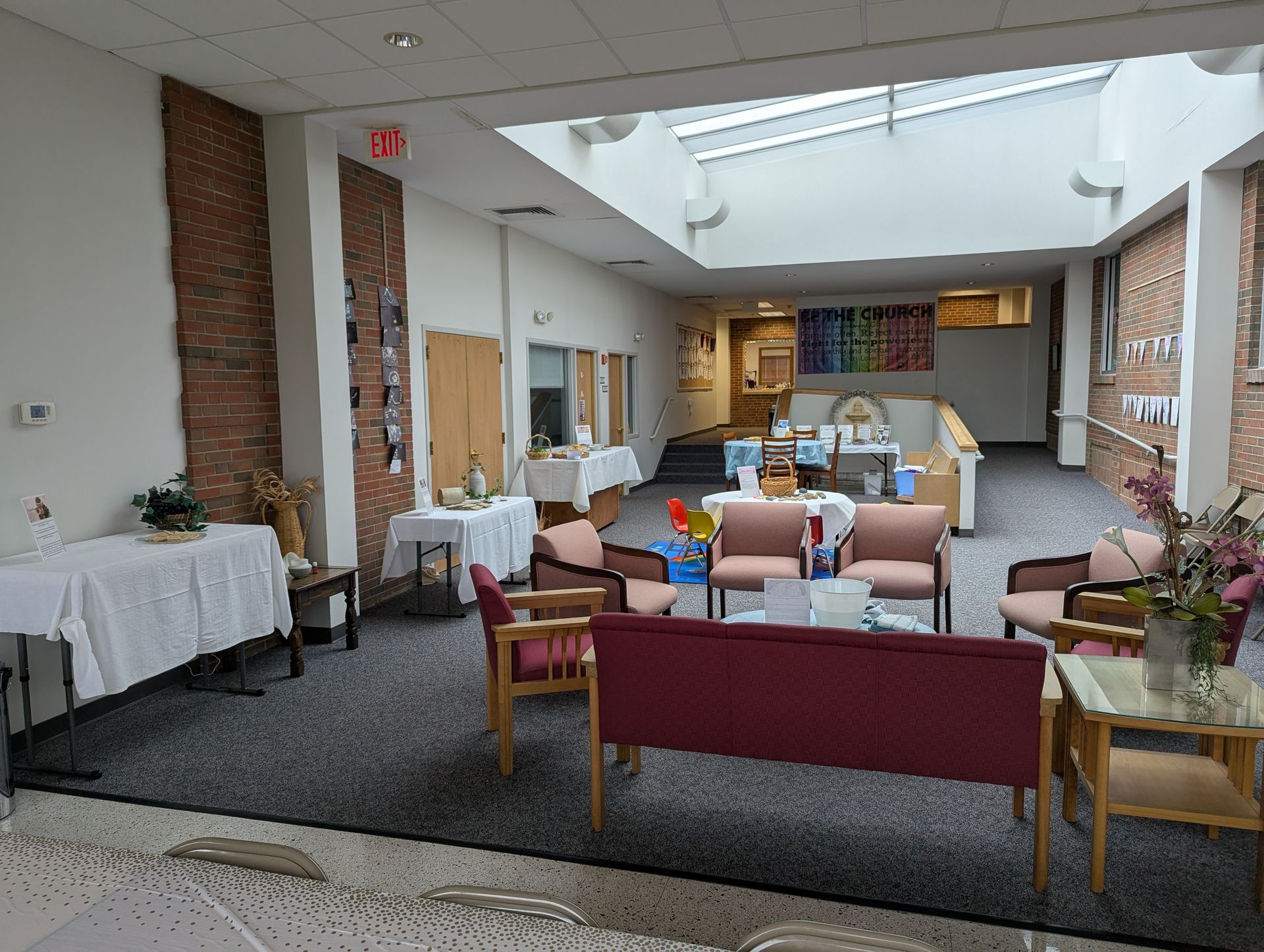 Bright lounge with couches, tables, and flowers under a skylight in a nursing home or care facility