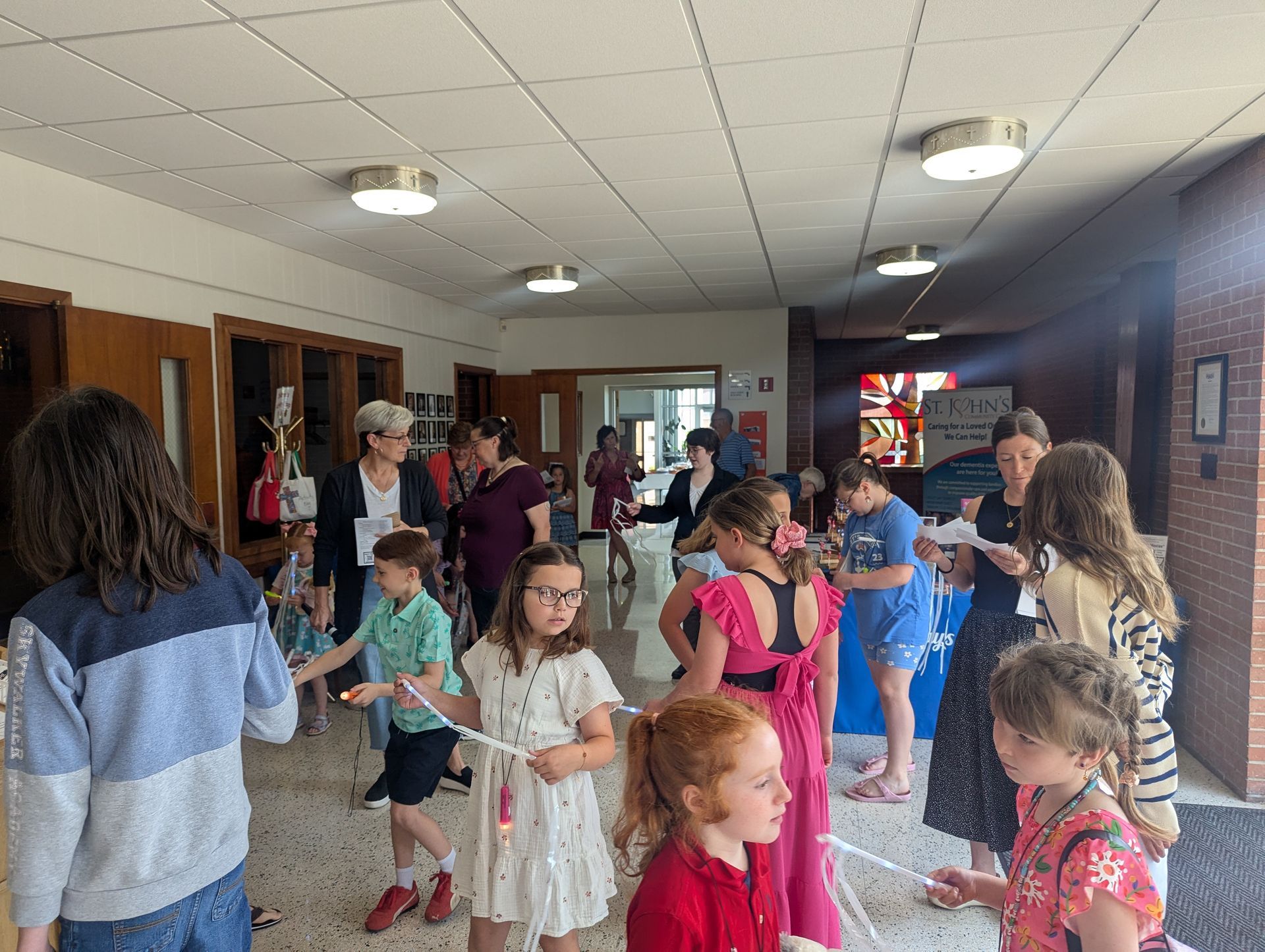 People dancing and socializing in a hallway with tiled ceiling and wooden walls