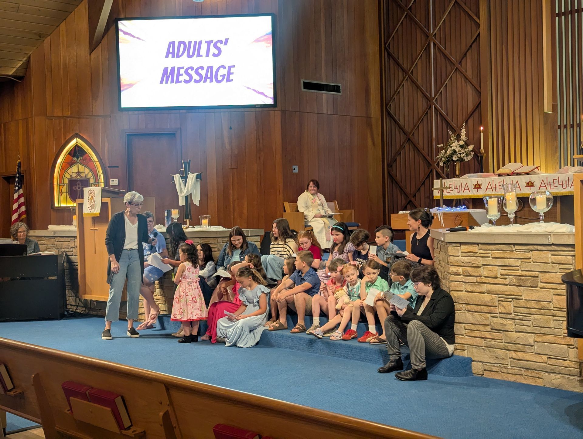 Children and adults seated on a church stage under an 