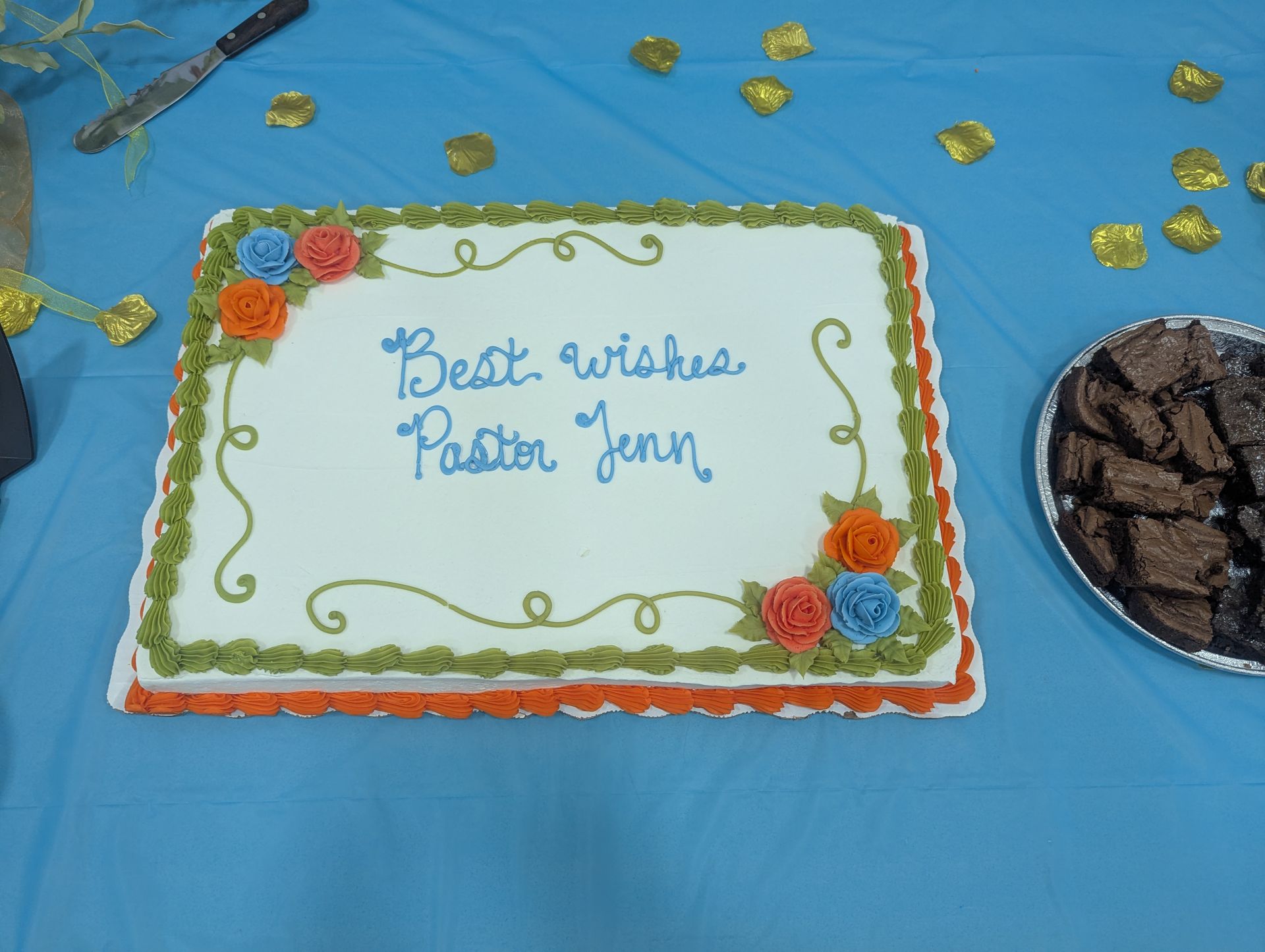 Birthday cake with “Best wishes Father Youn” written in blue icing on a blue tablecloth