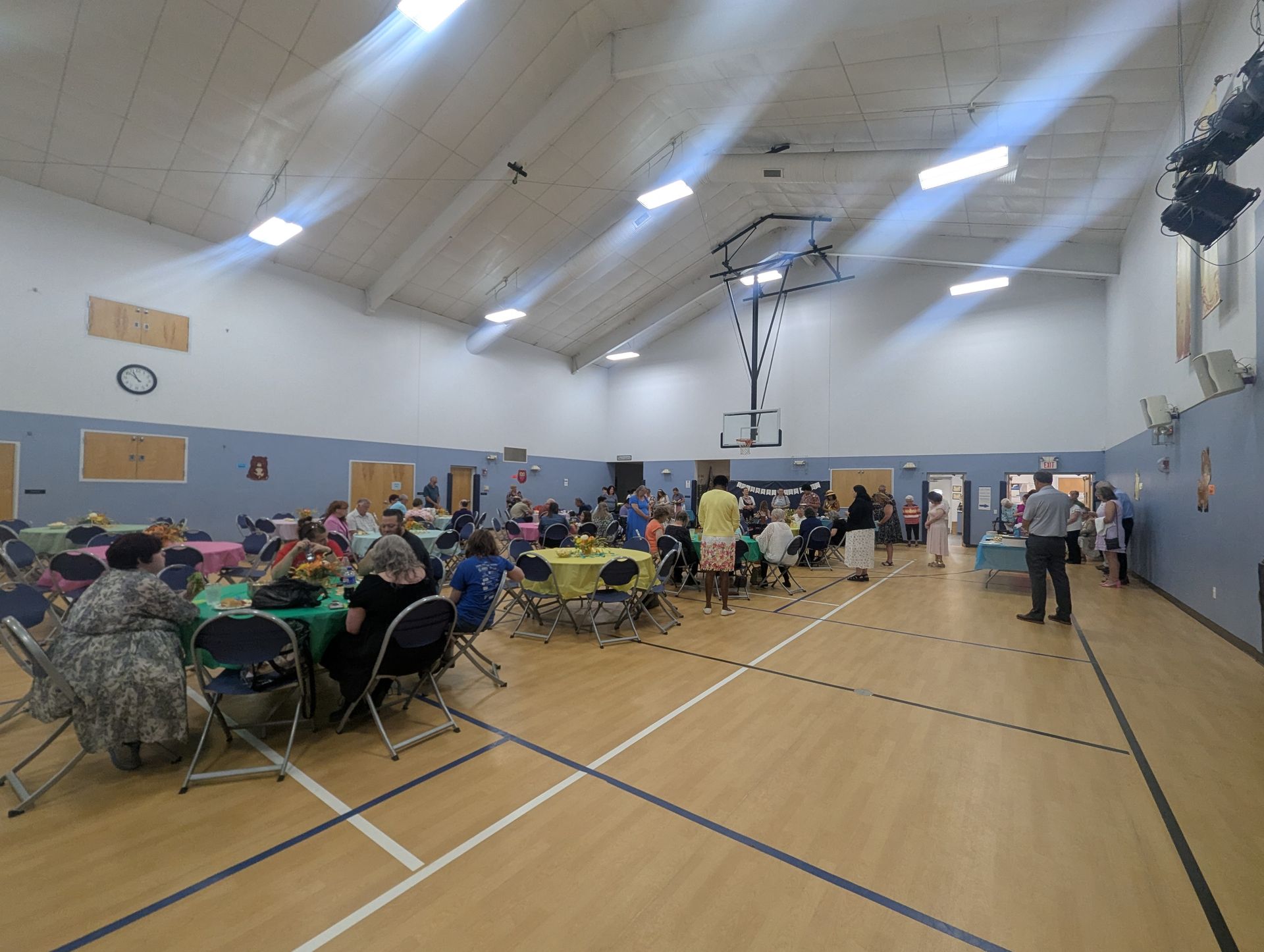 Indoor gym with people seated at tables during a community gathering or event