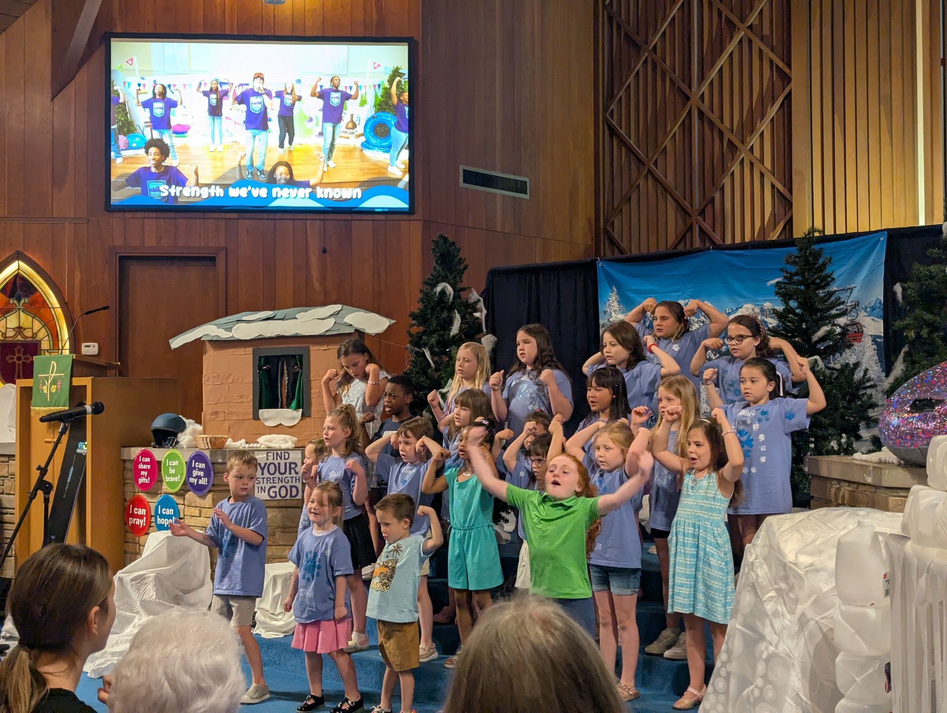 Children on a church stage performing with raised hands during a festive program
