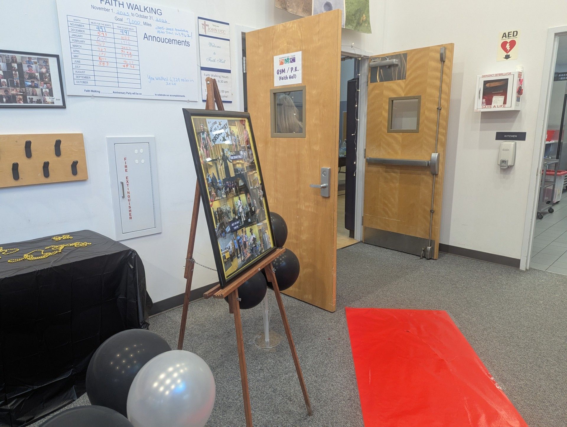 Office room with open wooden doors, a display board on an easel, and balloons on the floor.