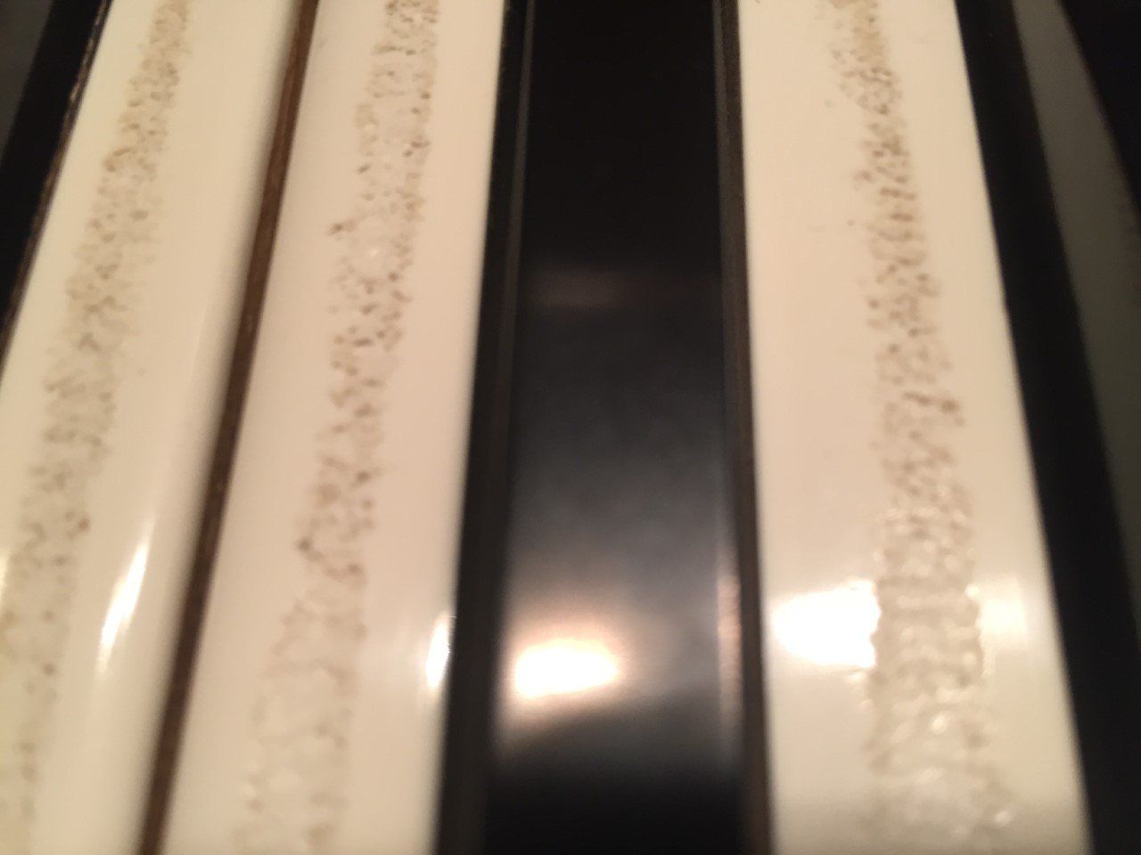 Close-up of worn white and black piano keys with dust along the edges