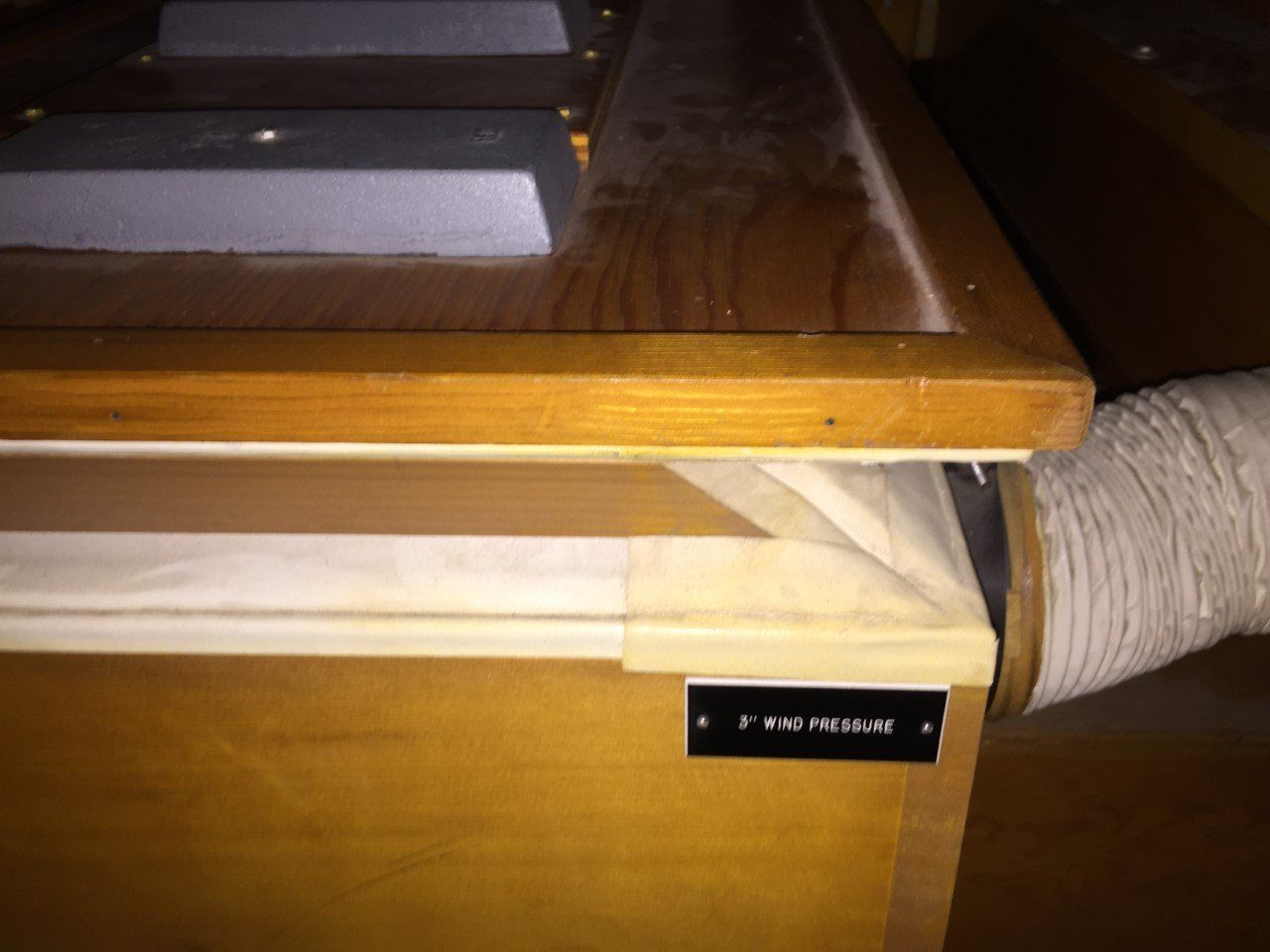 Wooden desk with a black label and a thick cable or hose exiting the right side