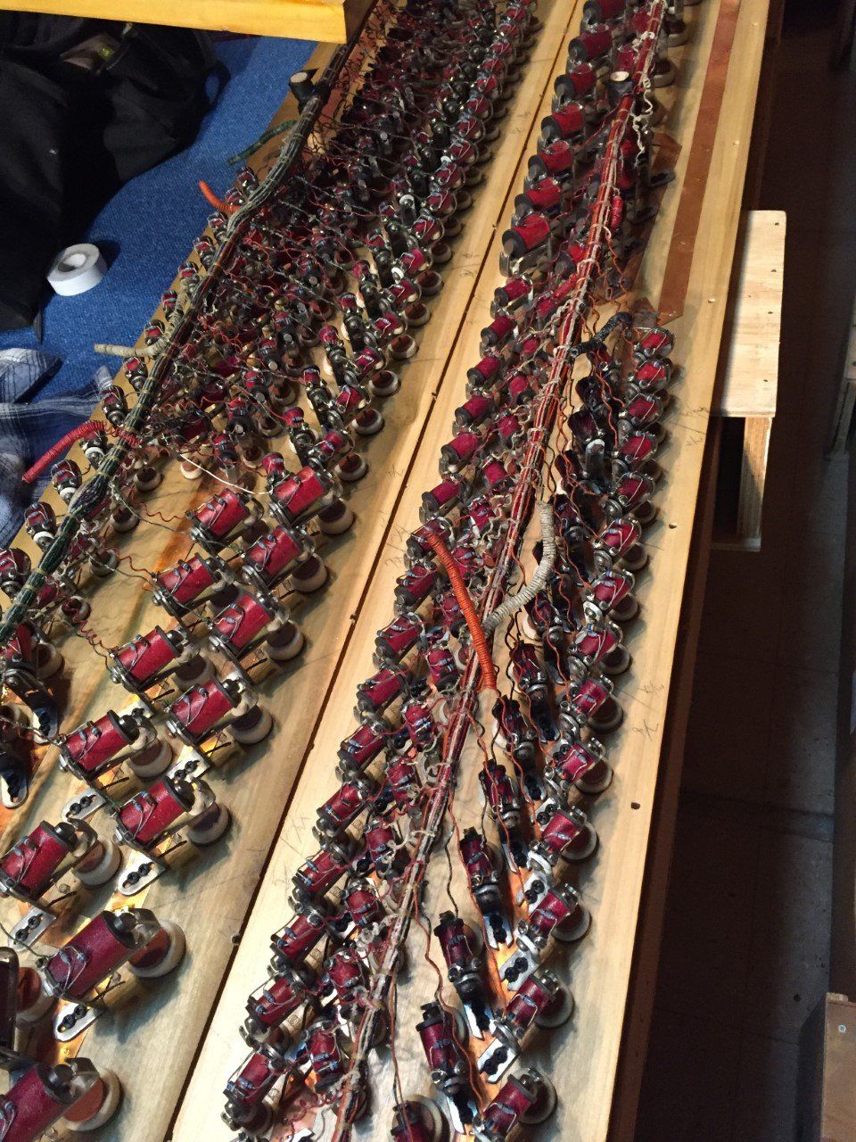 Rows of red-and-gold beaded bracelets displayed on a wooden tray.