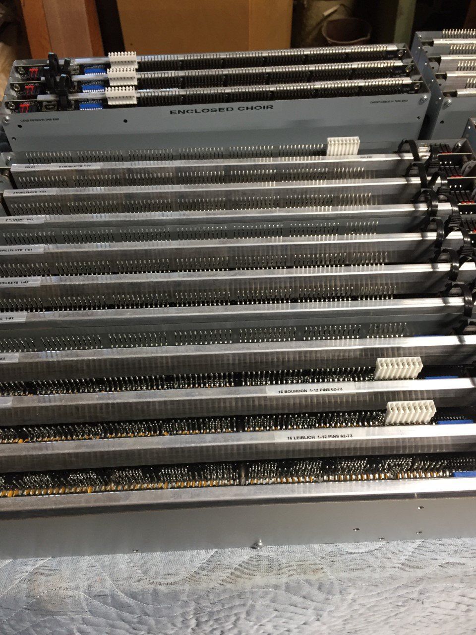 Stacked long metal rods in a workshop tray, with labels on several bundles.