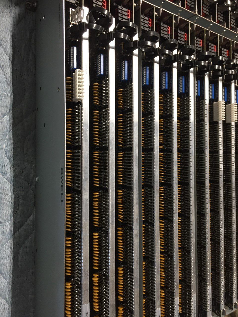 Rows of tall black mechanical components with orange wiring in a server rack-like setup