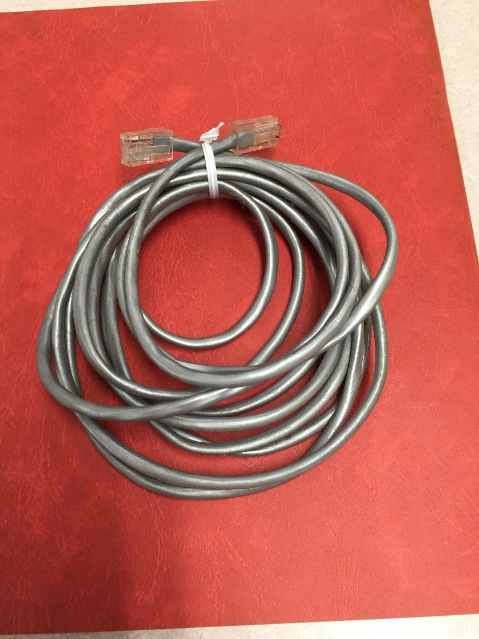 Coiled gray Ethernet cable with clear connectors on a red background