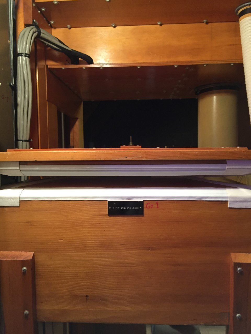 Wooden cabinet with an open shelf, cables on the left, and a white cylinder on the right.