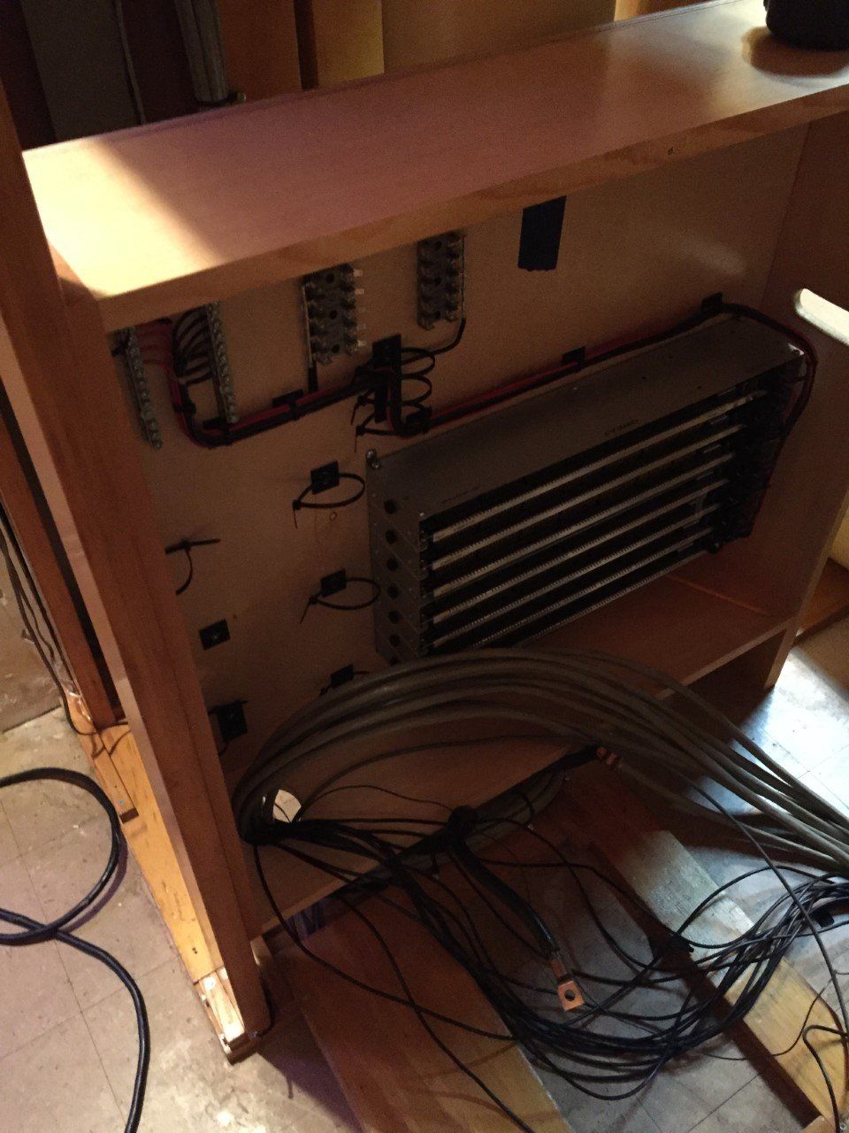 Open cabinet with tangled black cables and electronic components inside