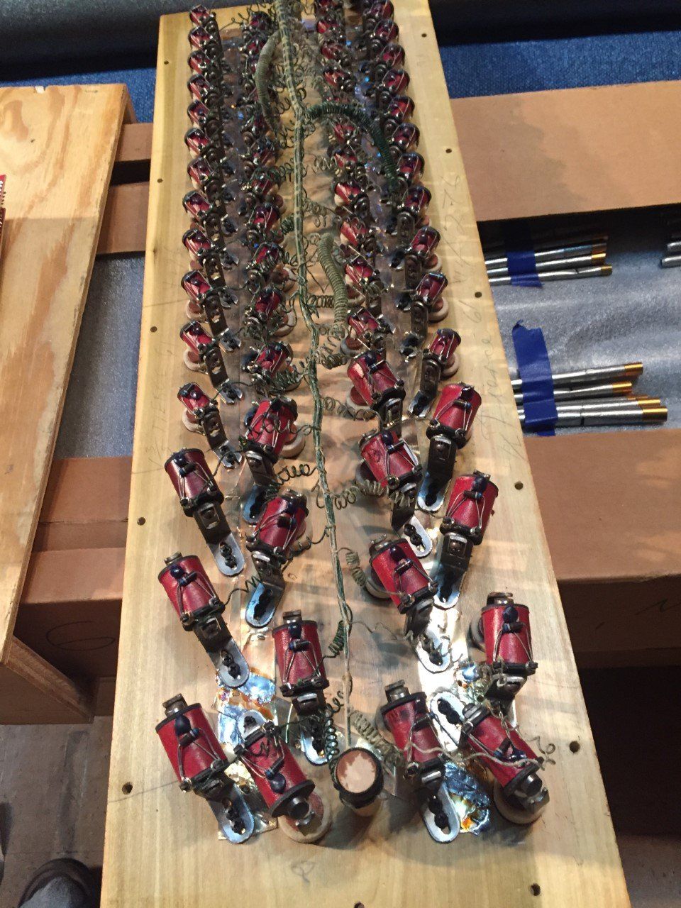 Rows of small red-and-black toy vehicles arranged on a wooden board.