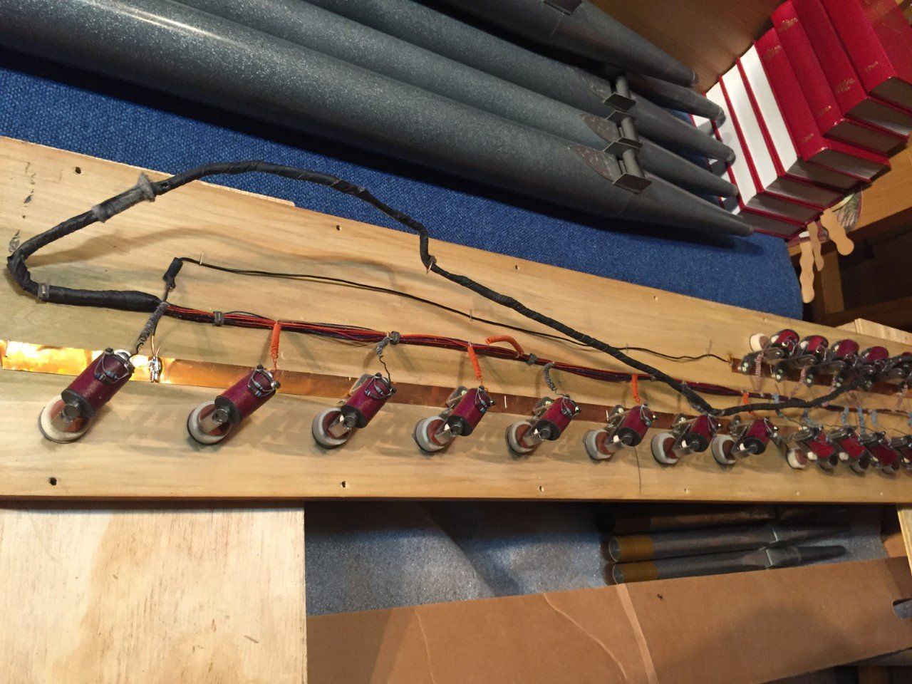 Wooden board with rows of red-handled tools or lights and black cables on a shelf