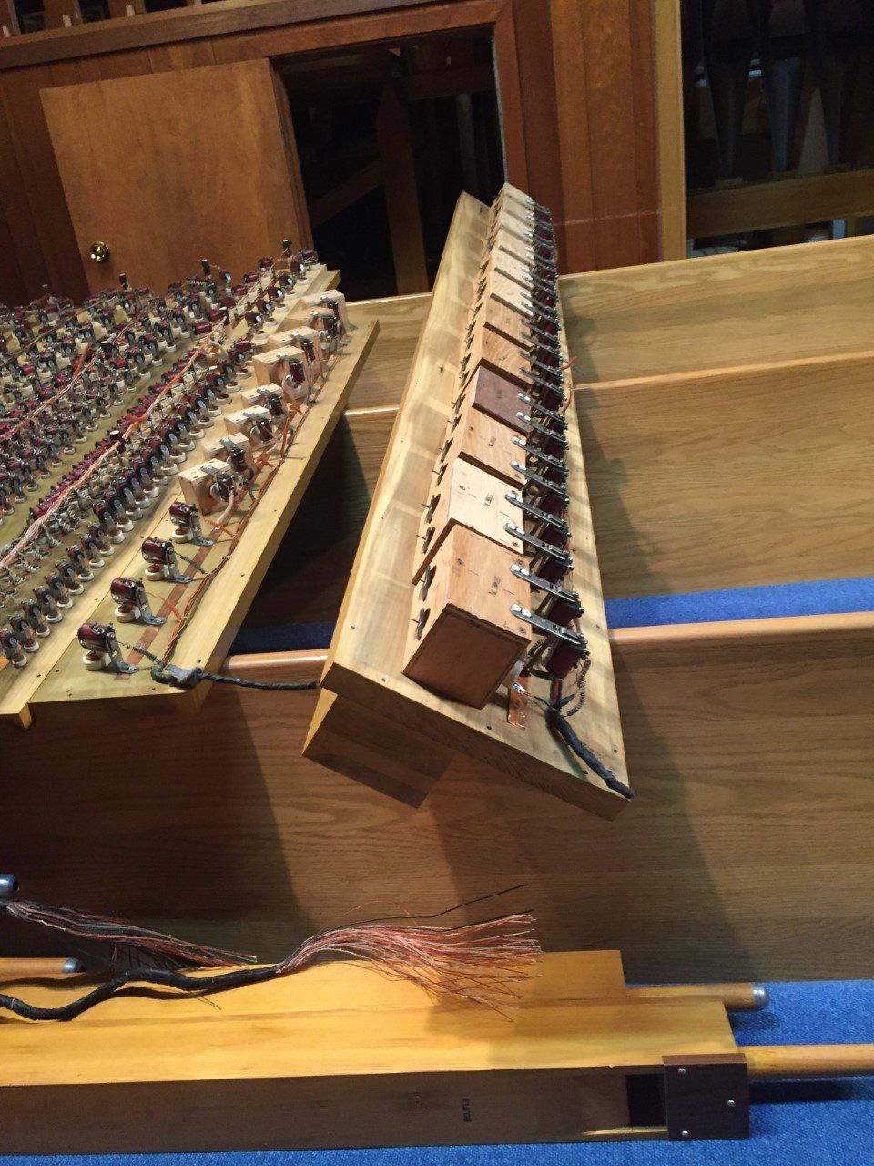 Close-up of a wooden piano action mechanism with exposed hammers and strings inside a piano.