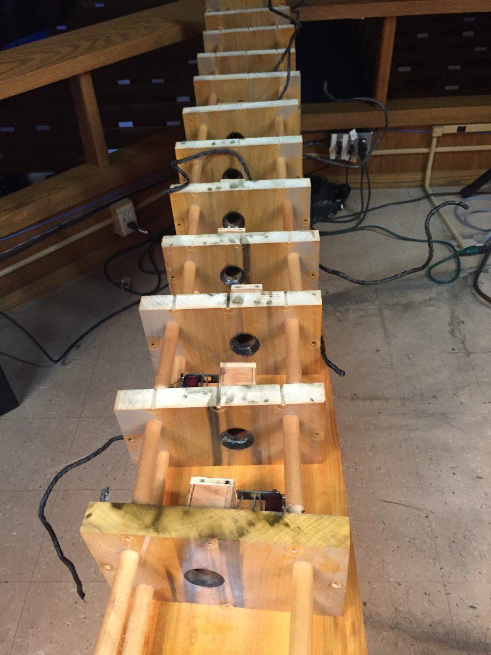 Wooden test rig with a row of small black sensors or cups mounted along a central beam on a workshop floor