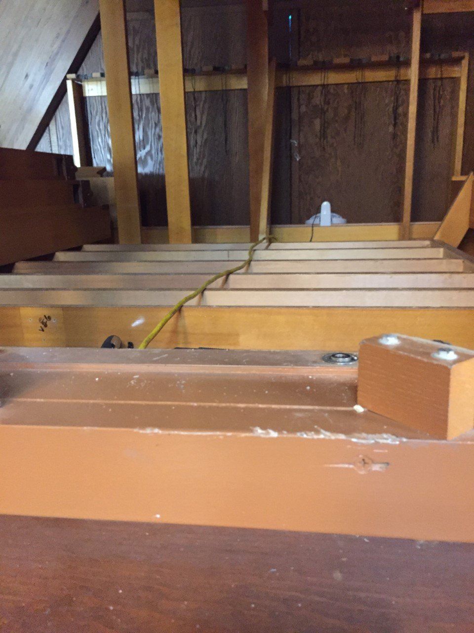 Interior of an unfinished attic with exposed wooden beams and floor joists, seen from a hatch opening