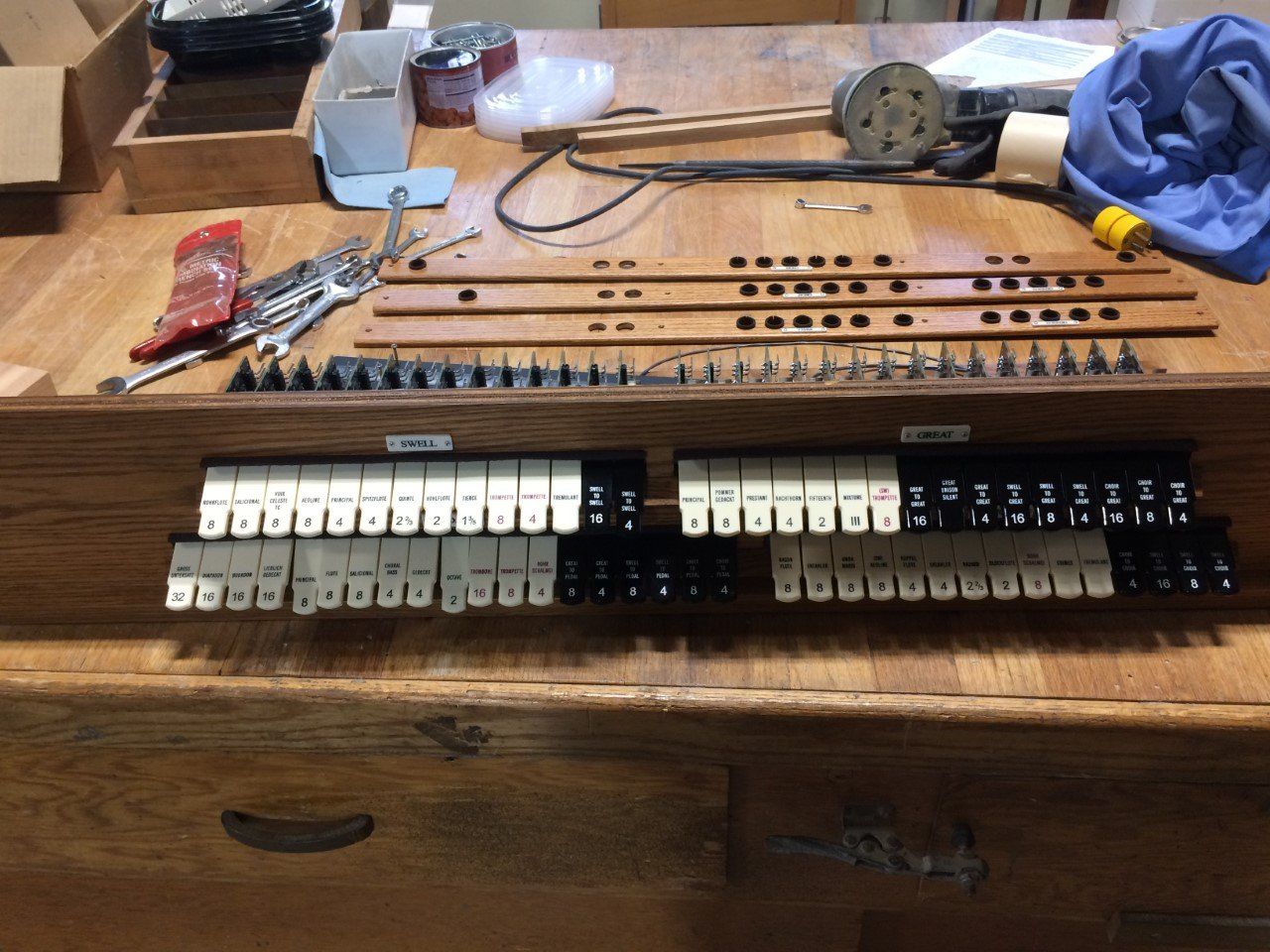 Wooden workbench with an organized set of screws, tools, wires, and small black-and-white keyboard-like components