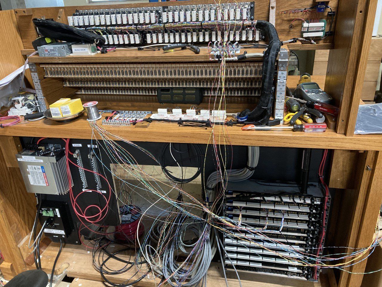 Wooden workbench with tangled cables and electronic equipment in a cluttered workshop space
