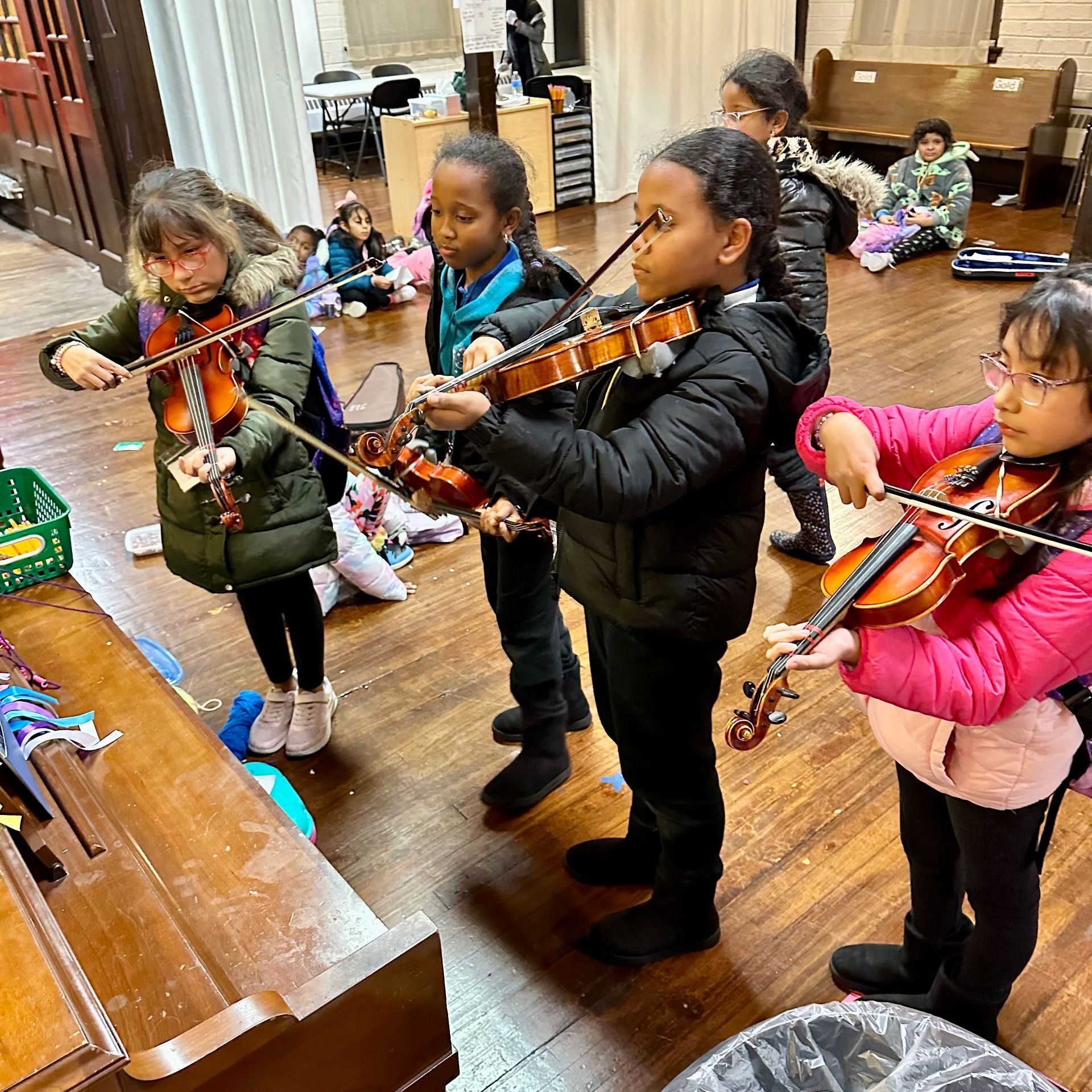 A group of young girls are playing violins in a room.