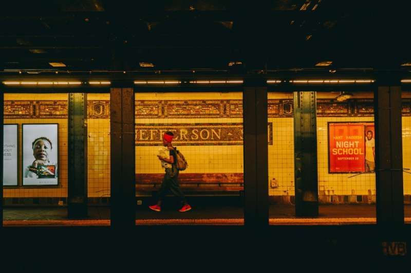 A man is walking through a subway station at night.