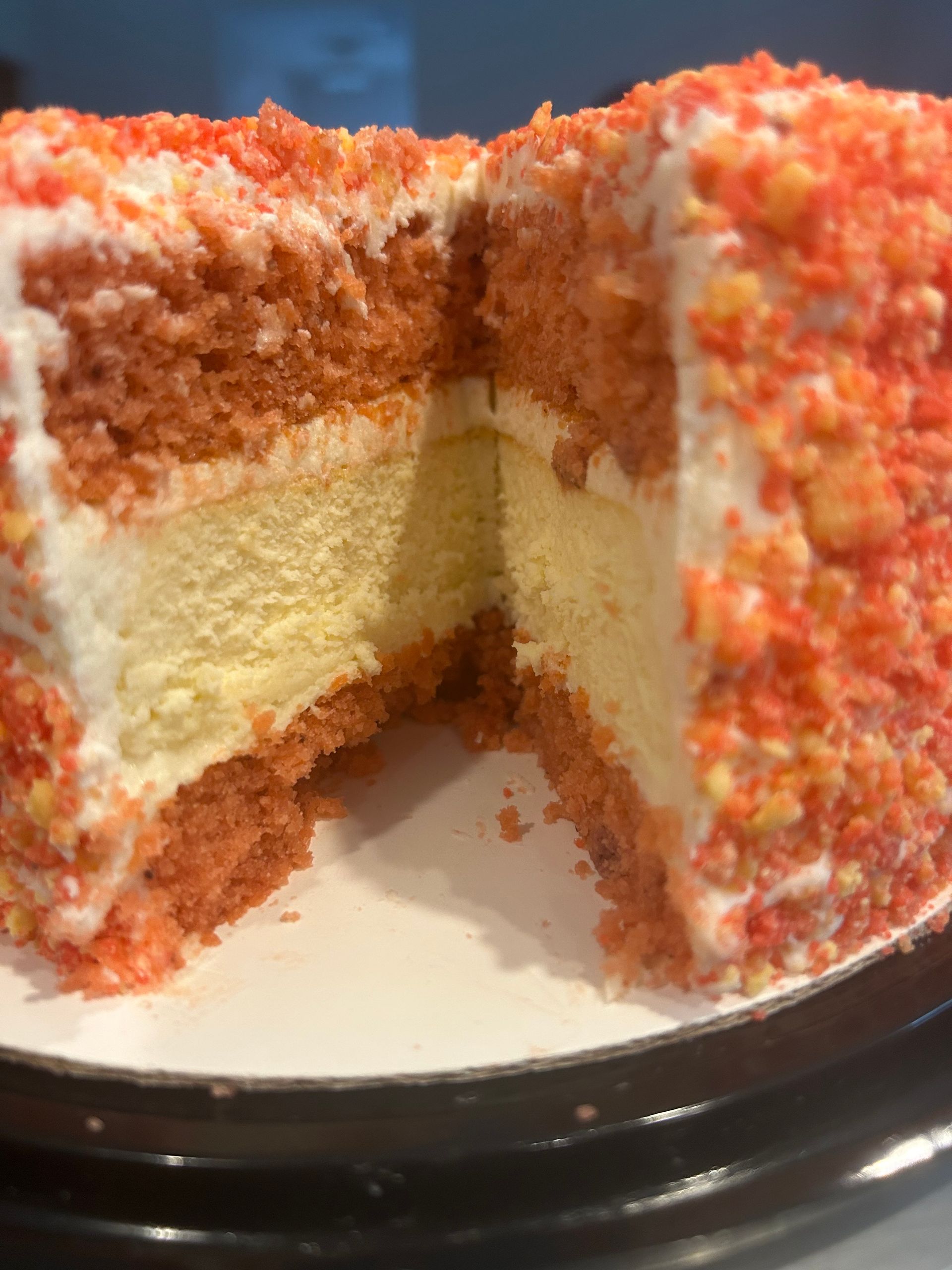 A cross-section of a red velvet cake with a cheesecake center, covered in red crumbs.