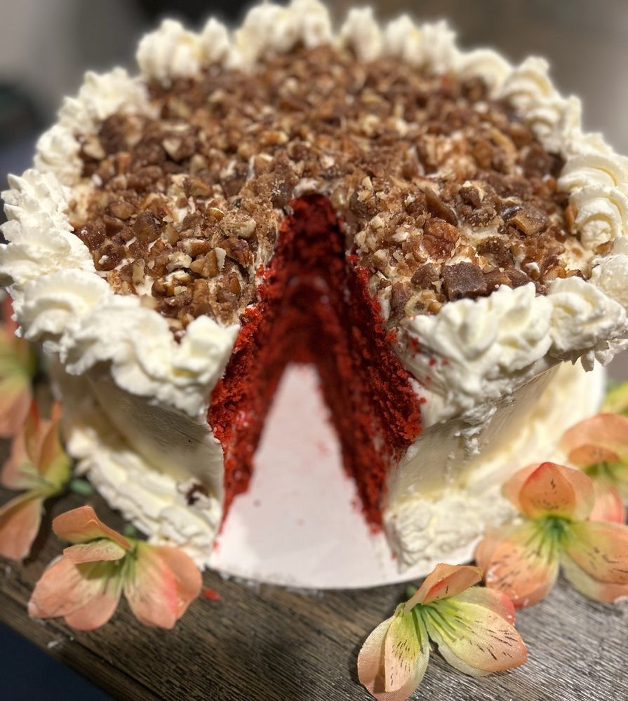 Red velvet cake with white frosting and pecan topping, a slice removed.