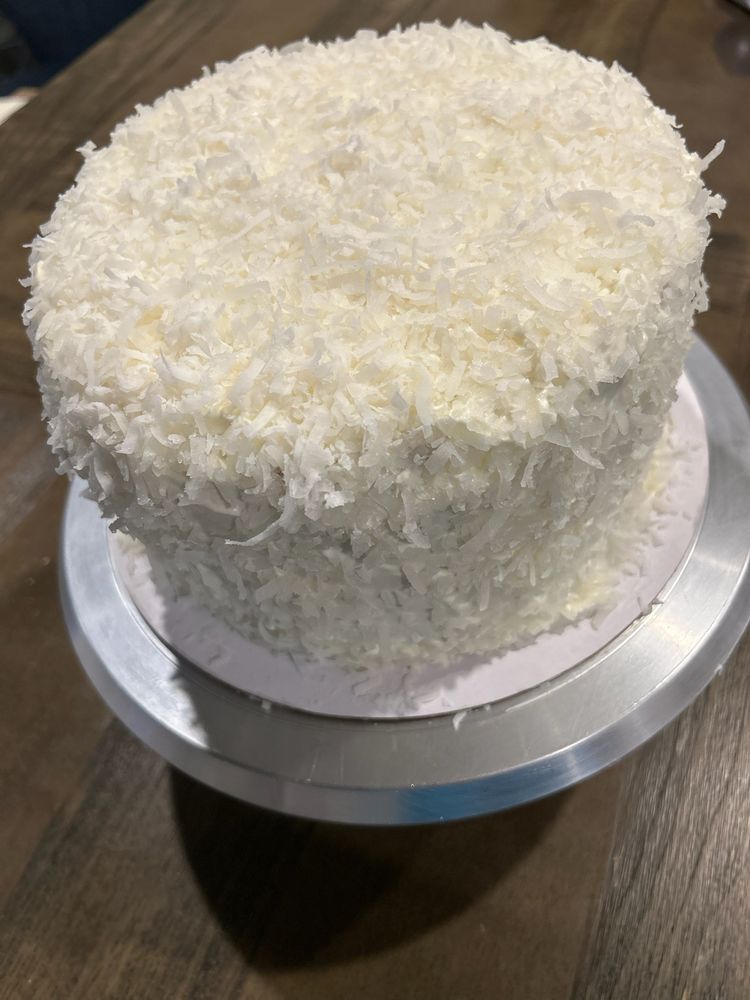 Coconut cake on a silver cake stand, covered in shredded coconut.