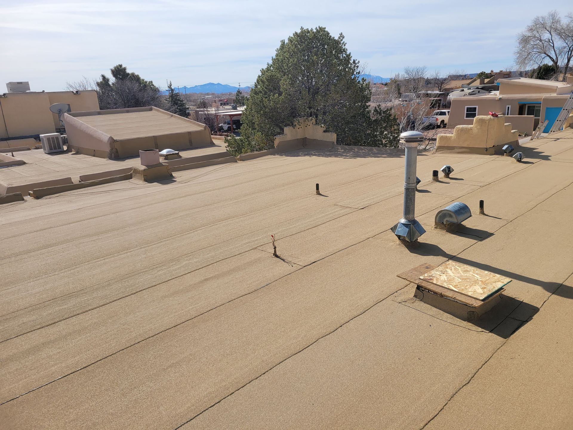 Worker installing roofing on a sloped roof under a blue sky