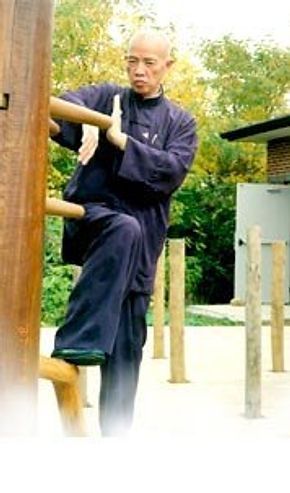 A man is practicing martial arts on a wooden dummy.