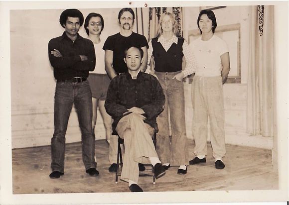 A group of people posing for a picture with one man sitting in a chair