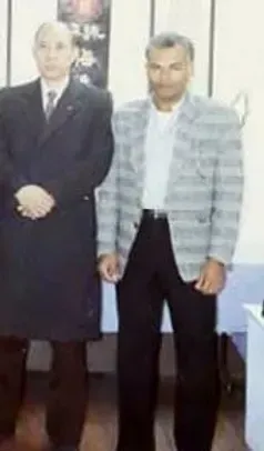 Two men in suits and ties are standing next to each other in a room.
