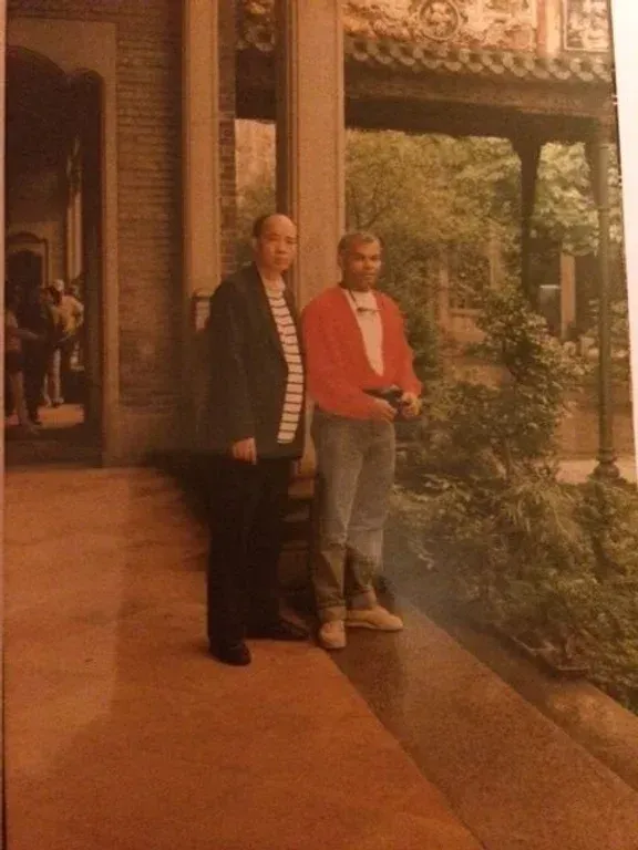 Two men standing next to each other in front of a building