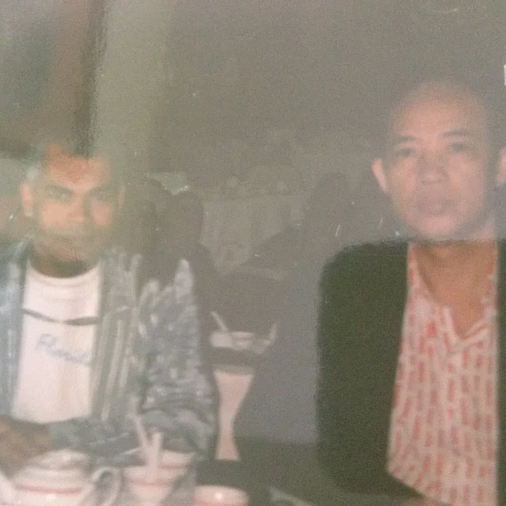 Two men are sitting at a table with cups and saucers