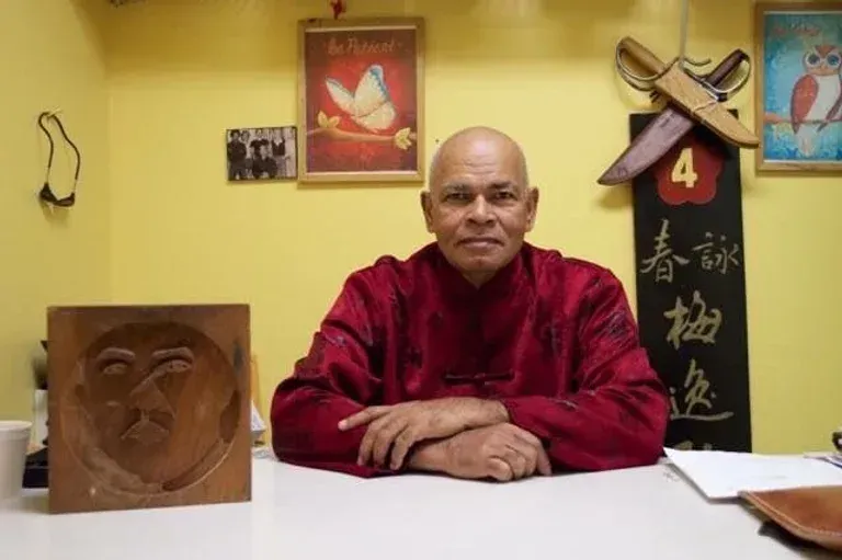 A man in a red shirt is sitting at a desk