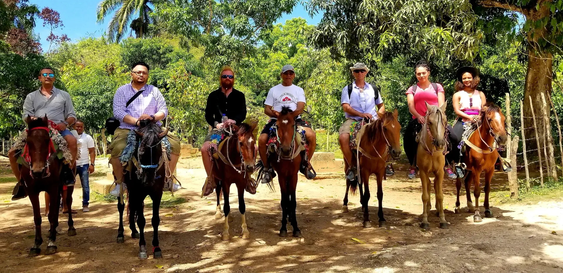A group of people are riding horses on a dirt road.
