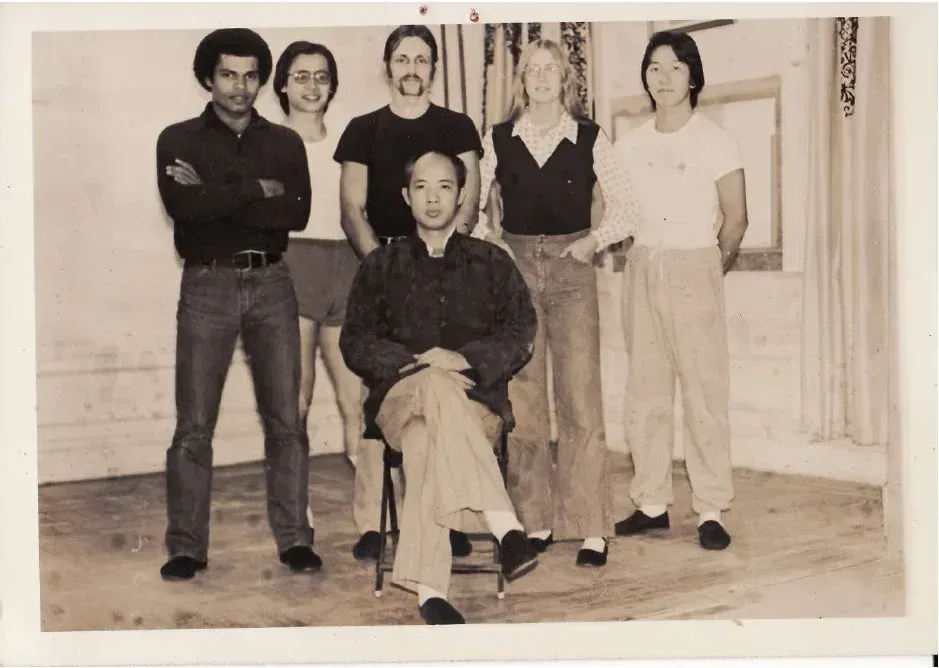 A group of people posing for a picture with one man sitting in a chair