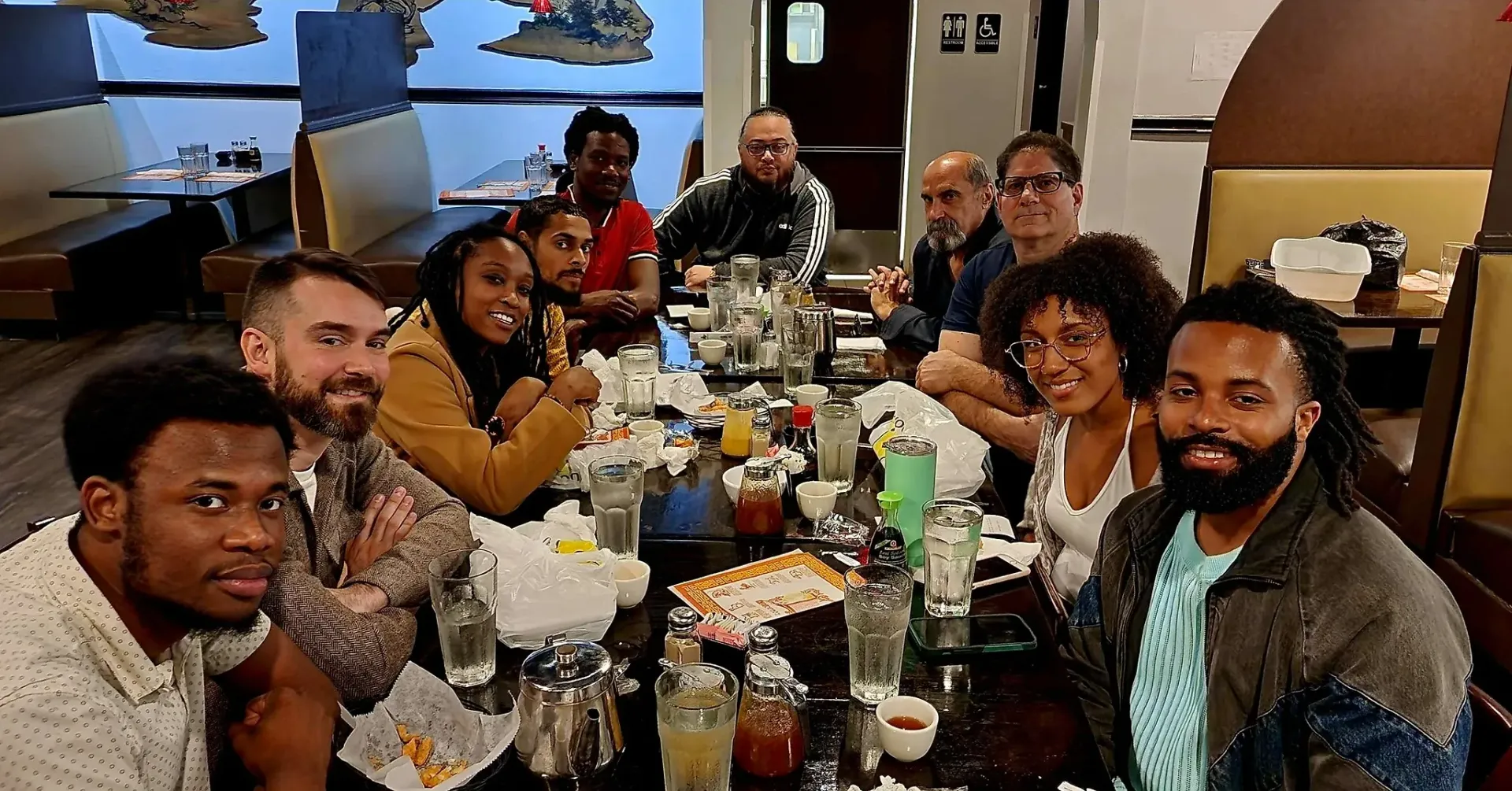 A group of people are sitting at a long table in a restaurant.