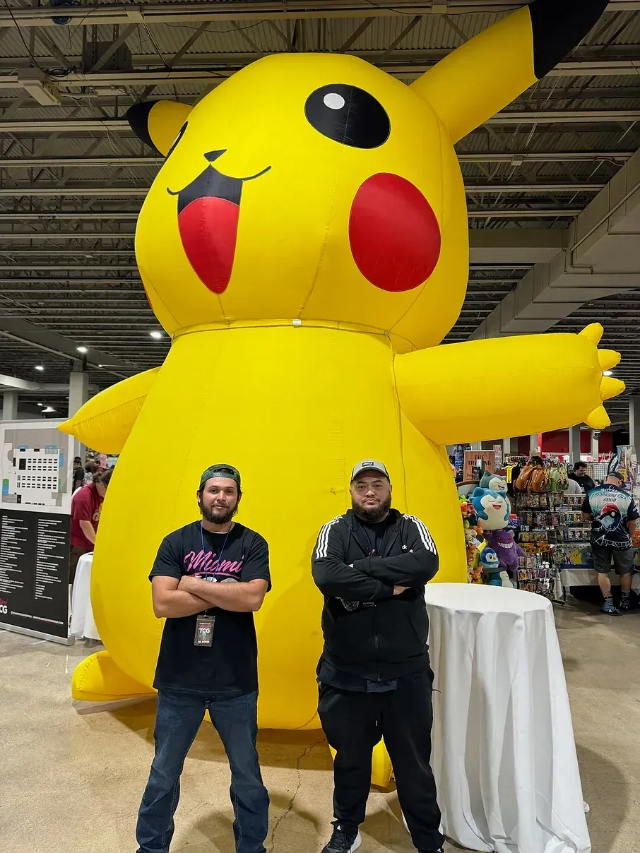 Two men are standing in front of an inflatable pikachu.