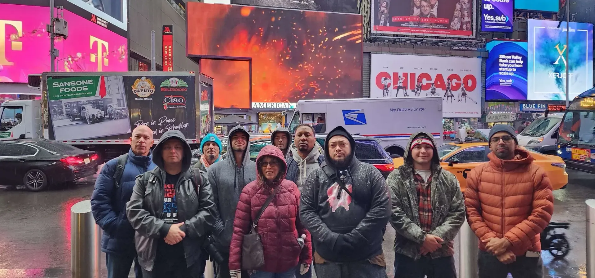 A group of people are standing in front of a billboard in a city.