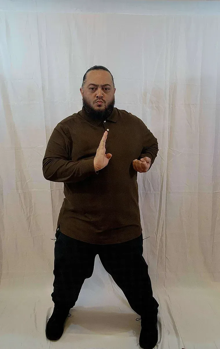 A man with a beard is standing in front of a white curtain.