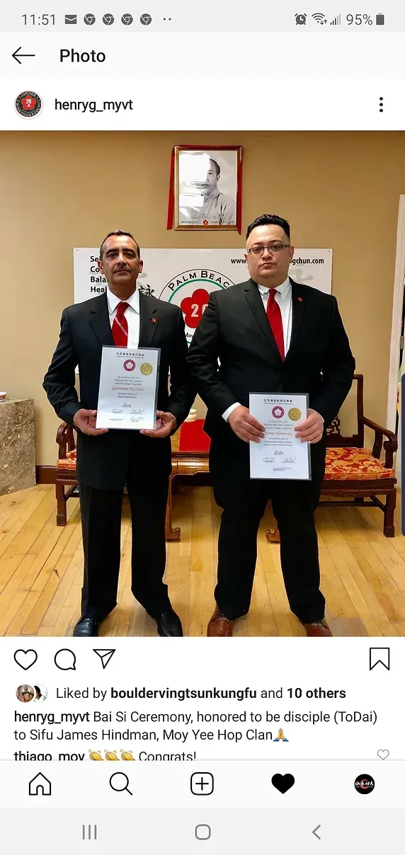 Two men in suits and ties are standing next to each other holding papers.