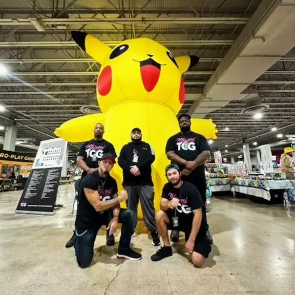 A group of men posing in front of an inflatable pikachu