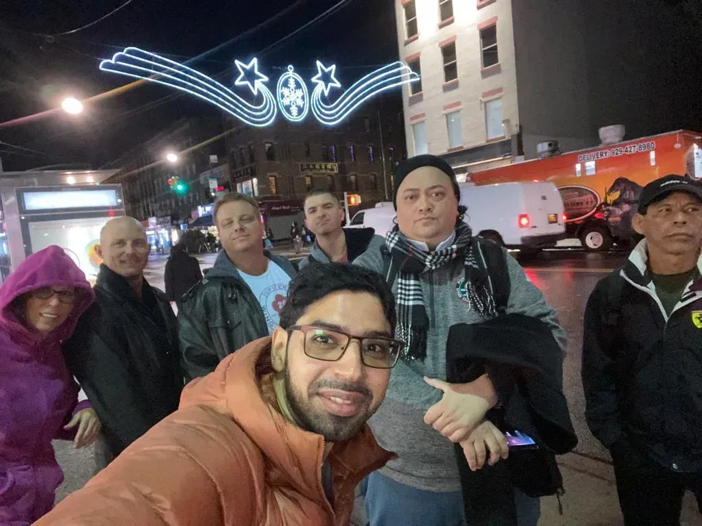 A group of people are posing for a picture on a city street at night.