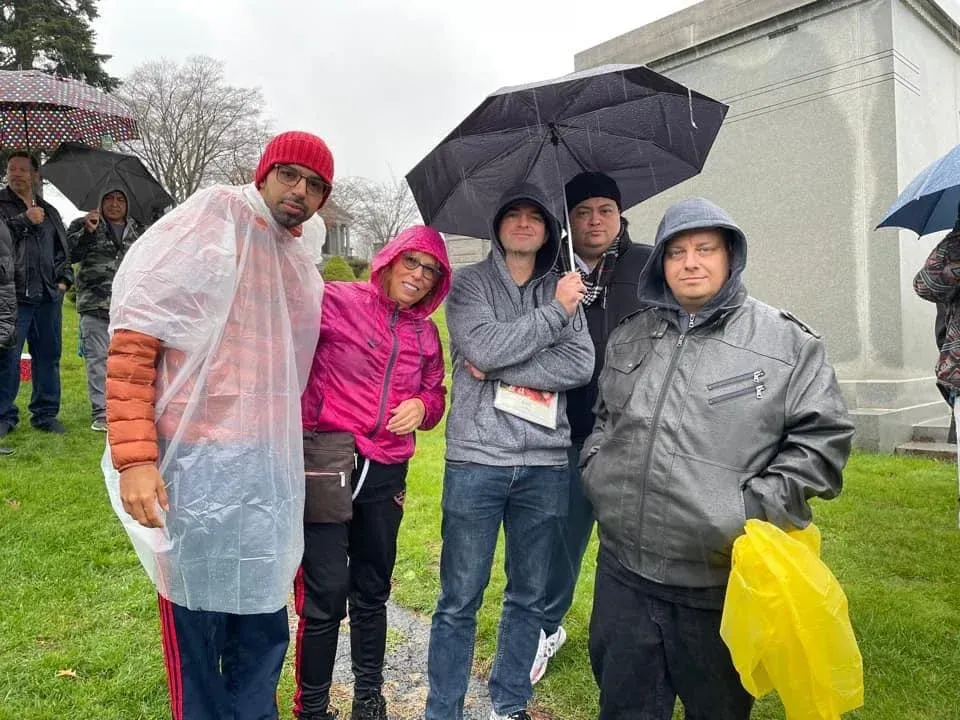 A group of people are standing in the rain holding umbrellas.