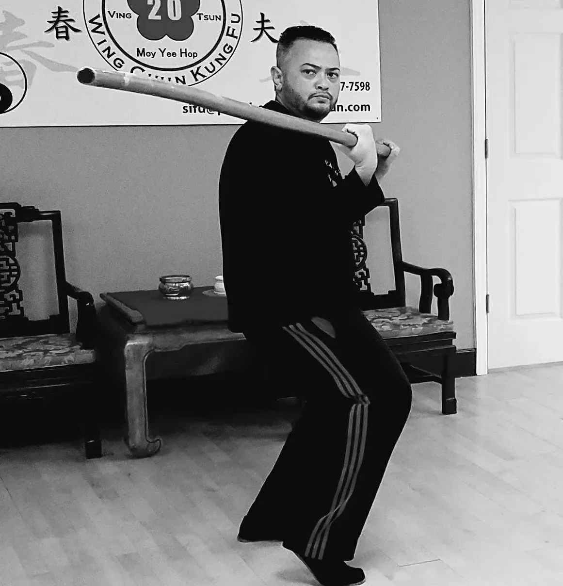 A man is practicing martial arts in front of a sign that says kung fu