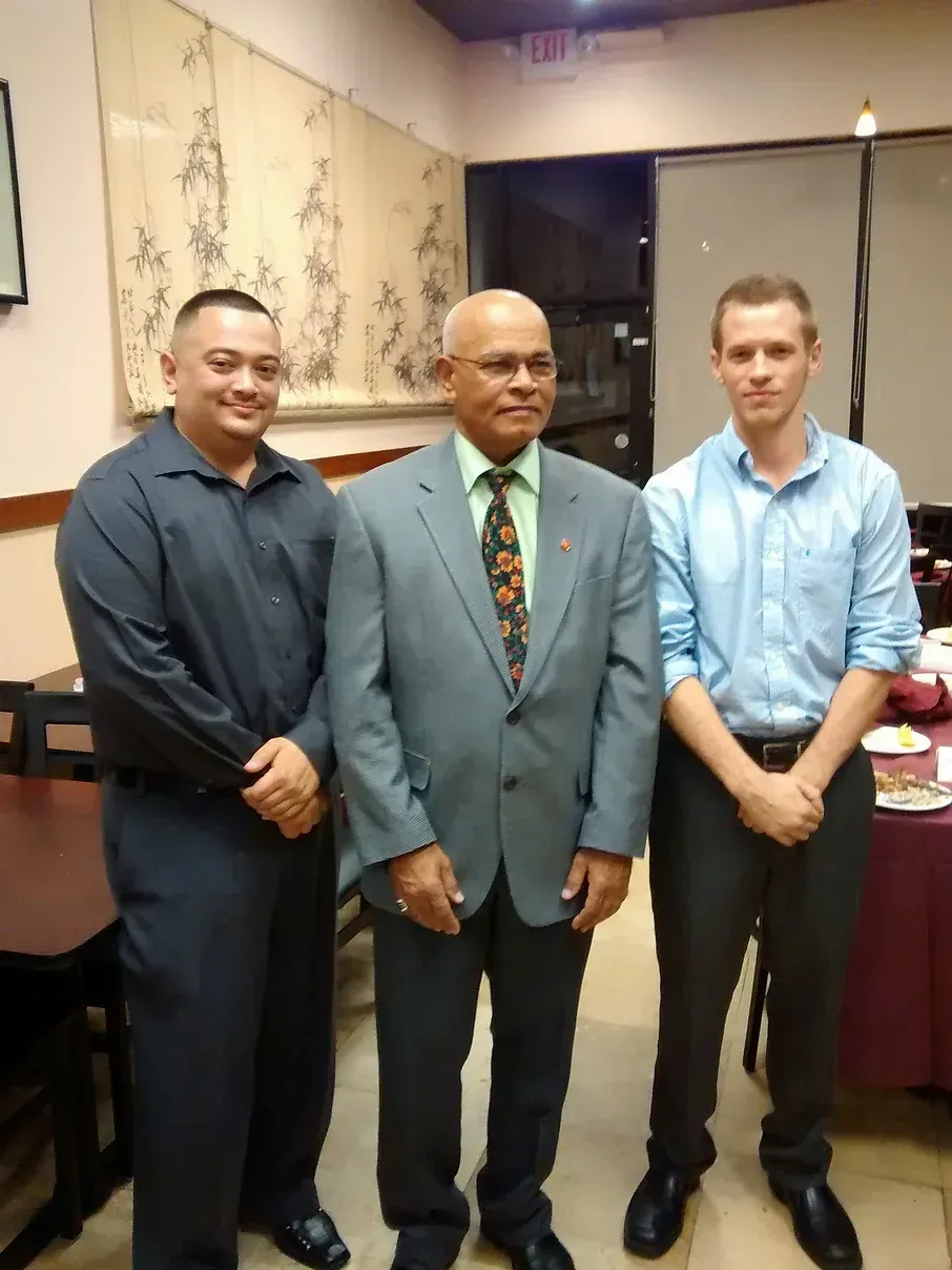 Three men in suits and ties pose for a picture