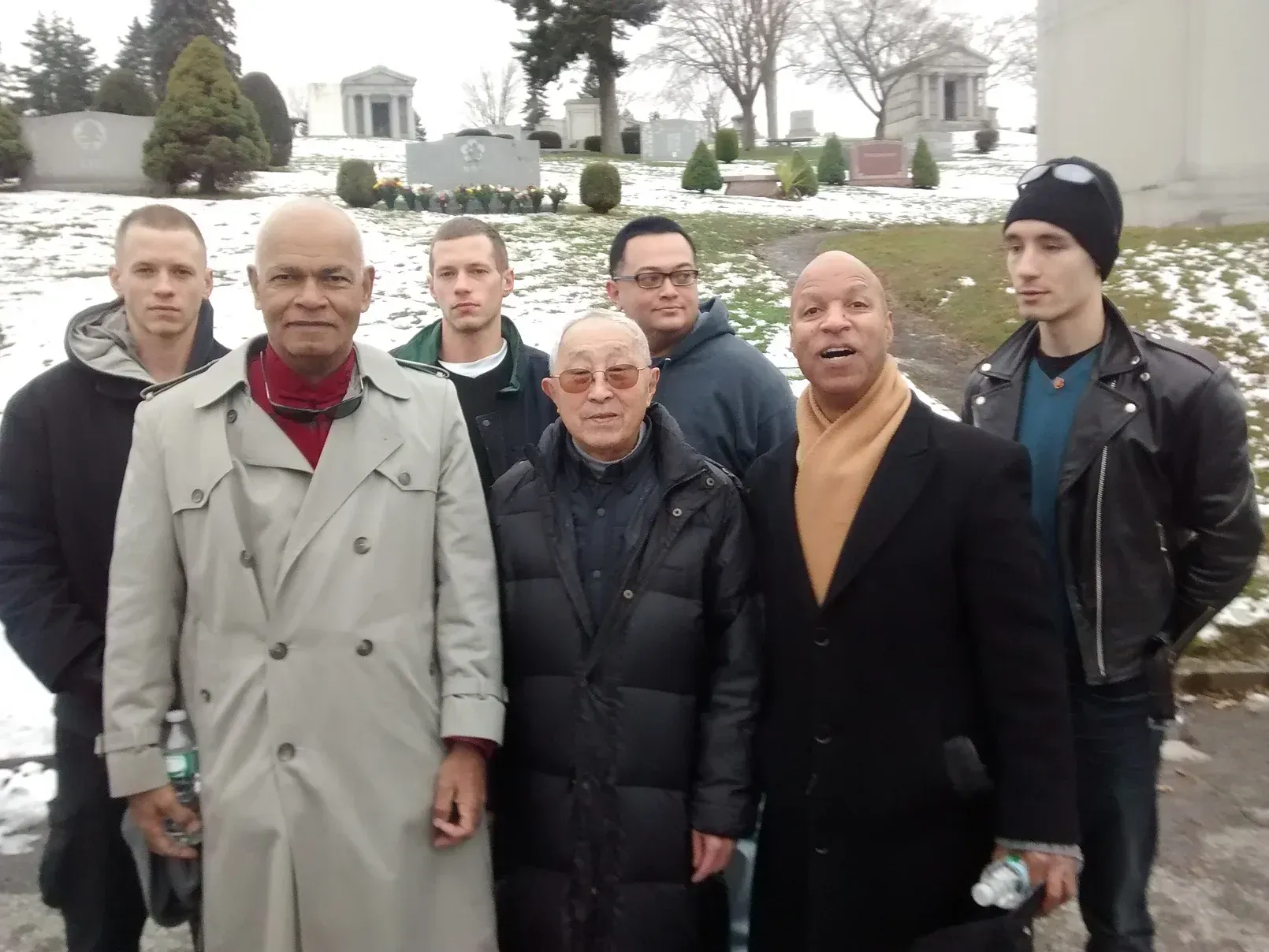 A group of men are posing for a picture in front of a cemetery