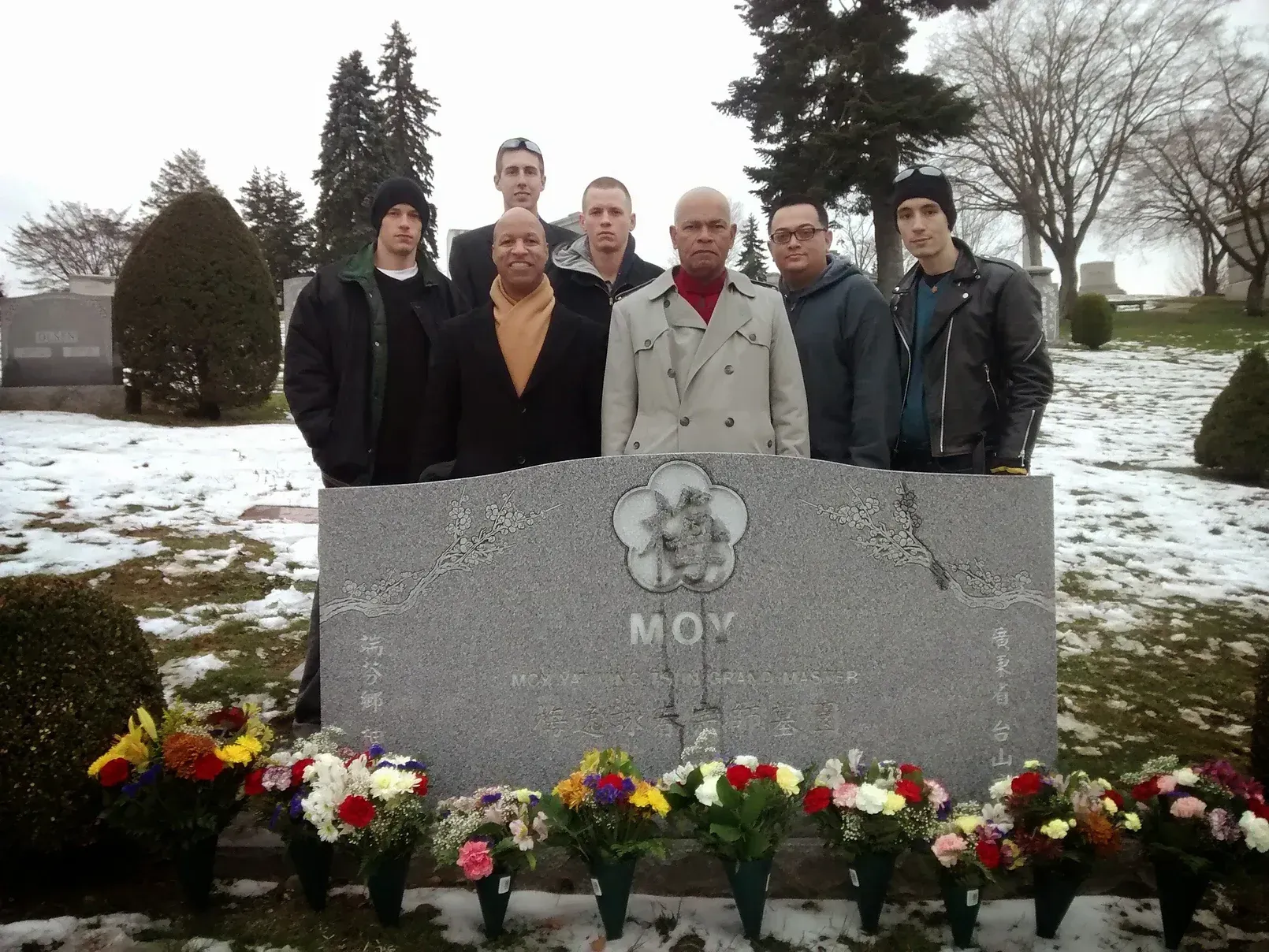 A group of men standing in front of a tombstone that says mok